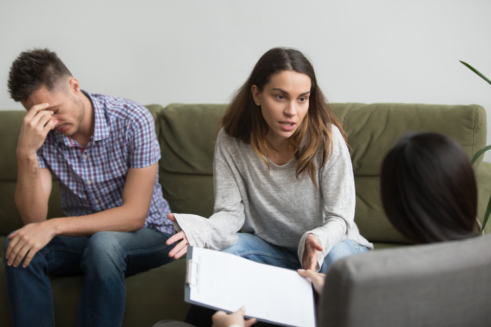 Couple in emotionally intense couples therapy session discussing relationship struggles and communication issues with a therapist.