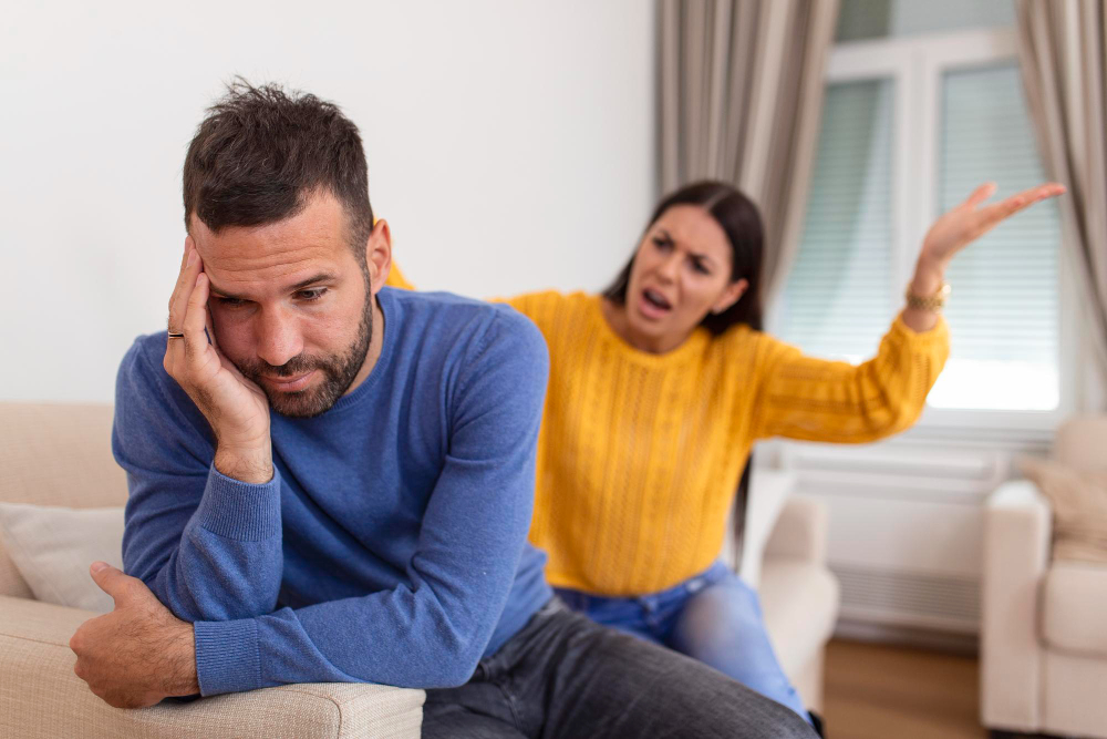 Emotionally withdrawn man shutting down during relationship conflict while partner reacts in frustration during an argument at home