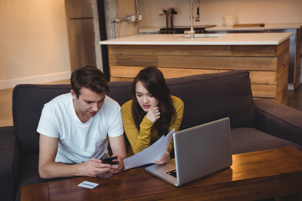 Couple sitting at home reviewing documents and having a serious discussion about unresolved relationship challenges and emotional processing after therapy.