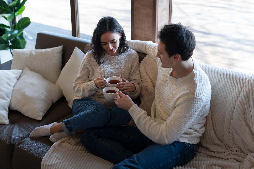 Couple sharing a calm conversation while sitting together at home, illustrating healthy emotional regulation, open communication, emotional connection, and relationship-building habits.