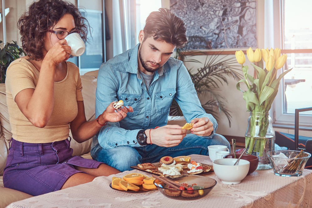 Emotionally distant couple sitting together at a dining table with limited interaction, illustrating relationship disengagement, reduced effort, and growing emotional disconnection.