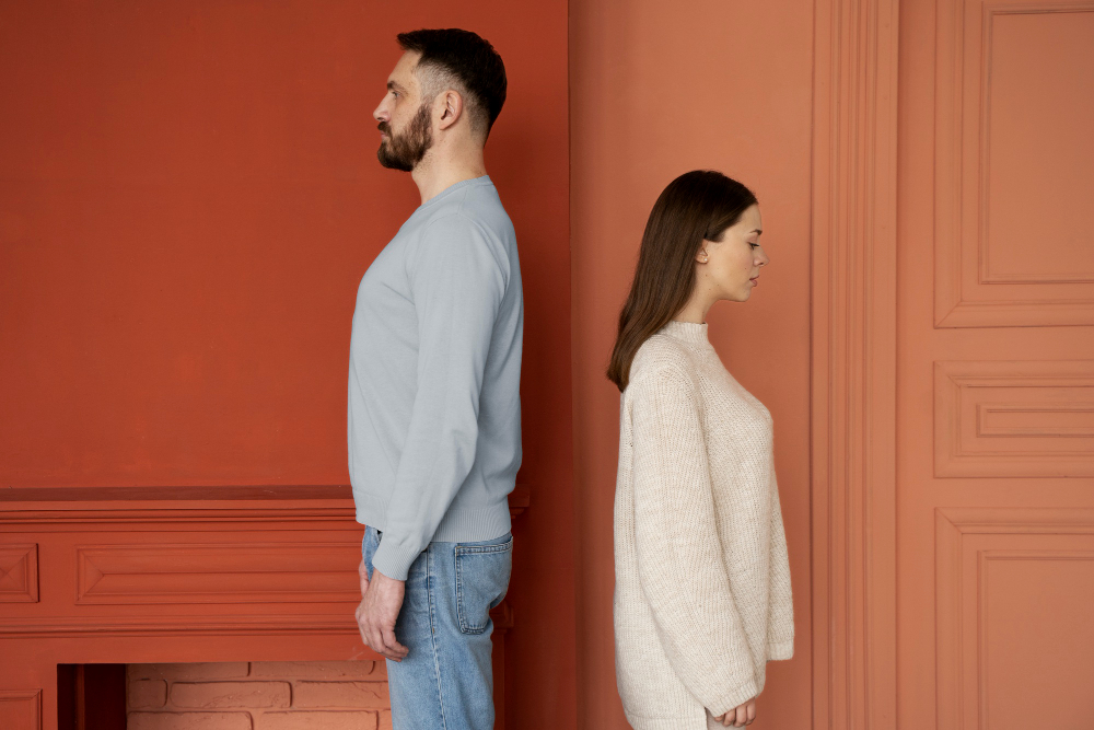 Couple standing back-to-back with emotional distance, illustrating keeping one foot out the door as a common sign of commitment issues in a relationship.